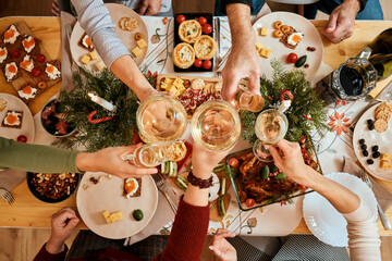 top view of a Christmas New Year's Eve decorated table,  five non-personalized people eating at the table, passing dishes to each other - obrazy, fototapety, plakaty