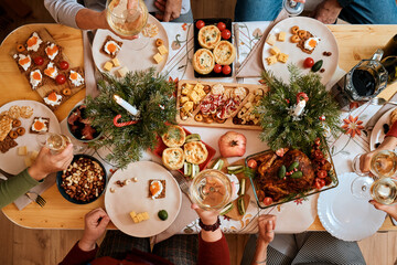 top view of a Christmas New Year's Eve decorated table,  five non-personalized people eating at the...