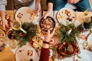 top view of a Christmas New Year's Eve decorated table, one person passes a plate of nuts to...