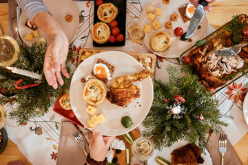 Christmas family dinner with family, relatives of different age and gender, Christmas decor, holiday table top view, celebrating the new year together, spread a hot dish, turkey leg, chicken in plates