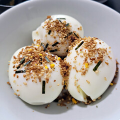 A close-up of a bowl filled with hard-boiled eggs, generously topped with furikake