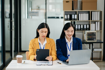 Asian business colleague business presents and explains and using laptop and tablet. Teamwork, financial marketing team, while sitting 