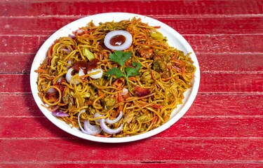 Chicken Chowmein in a Plate with Tomato Ketchup, Onion Slices and Salad Isolated on Red Wooden Background