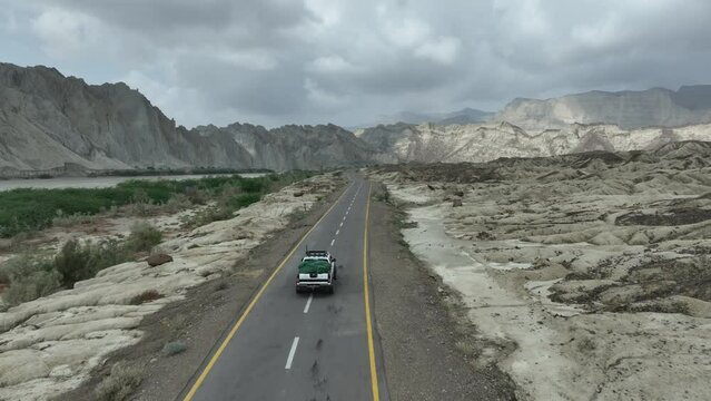 Drone tracking a Jeep car on the road driving towards beautiful landscape of mountain and hills Hingol Baluchistan