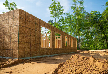 New home building site in early construction stage, with plywood on exterior walls and wood framing...