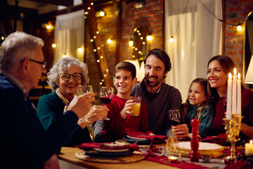 Happy multigeneration family toasting while gathering for dinner at Christmas.