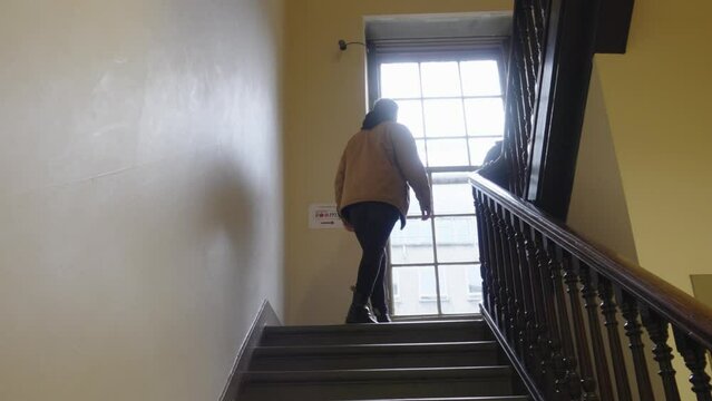 Small group of people walking up flight of building stairs. Handheld