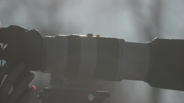closeup pan of woman photographing with long zoom lens outdoors