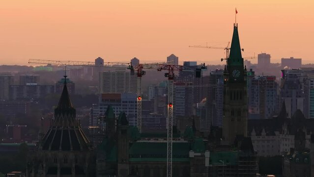 Telephoto drone shot of the Canadian parliament and peace tower with many cranes and buildings under construction in the growing city