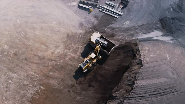 Drone video of a front end loader loading a rock truck with aggregates from a stockpile in a mine