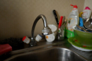 Old water tap in the kitchen against the background of dishes, cups