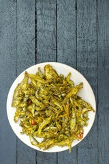 Small Fish Dry Gravy in a Plate Isolated on Black Wooden Background with Copy Space