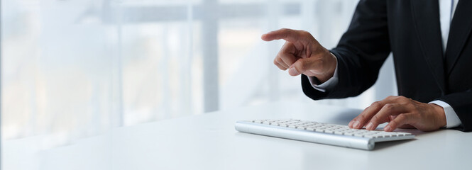 Close-up photo of businessman's hand Professional pointing at data on laptop computer screen, smartphone on white table at office online business ideas. copy space, banner, panorama