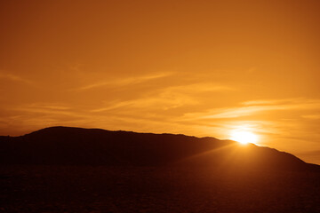 silhouette of black car standing on horizon line. sun rays on background of red, orange cloudy sky. sunlight.