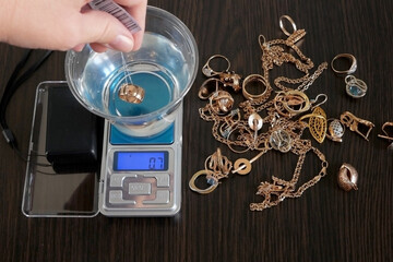pawnshop worker determines the ring of gold jewelry using the Hydrostatic weighing method by...