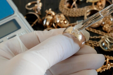 pawnshop worker uses chemical reagents to determine the authenticity of gold jewelry, evaluation of...