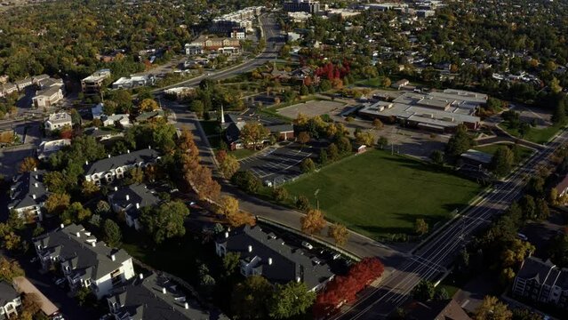 Tilt up dolly in aerial drone wide landscape shot revealing the stunning snowcapped rocky mountains of Utah with Salt Lake county below full of buildings and colorful trees on a warm sunny fall day