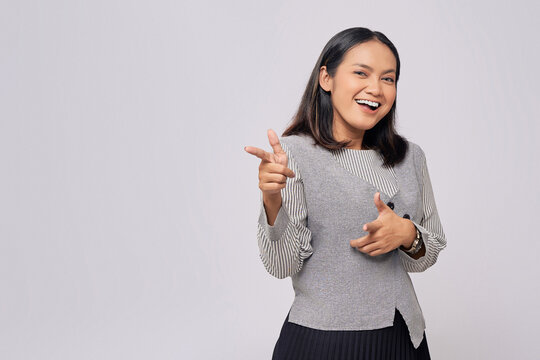 Smiling beautiful young Asian woman in casual clothes pointing fingers aside at copy space for your advertisement isolated on white background. People lifestyle concept