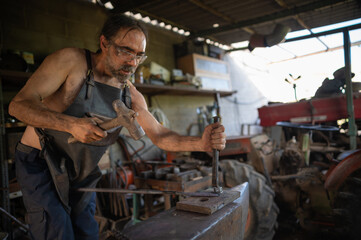 Side view of a blacksmith striking a piece of steel on a anvil.
