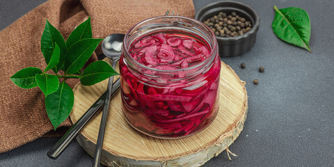 Jar with tasty pickled onions on black table. Cutlery, served meal ready to eat, trendy stand