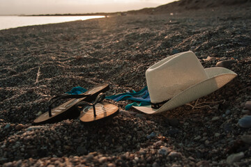 sombrero y chanclas en la arena de la playa

