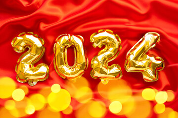 Foil balloons in the form of numbers 2024, New year celebration, Gold air balloons on red festive...