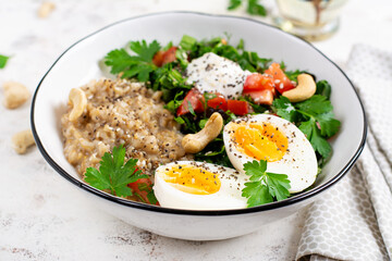 Breakfast oatmeal porridge with boiled eggs and fresh salad. Healthy balanced food. Trendy food.