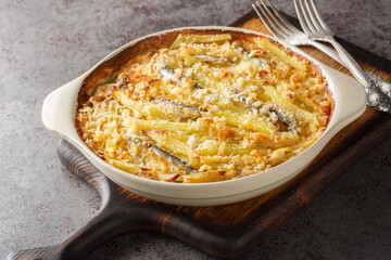 Homemade Jansson's temptation made from potatoes, onion and sprats closeup on the baking dish on...