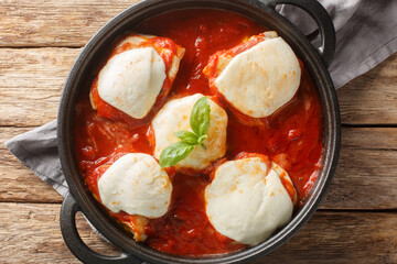 Authentic chicken pizzaiola is made with just 4 main ingredients chicken, tomato puree, basil and mozzarella closeup on the pan on the table. Horizontal top view from above