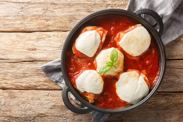 Italian chicken pizzaiola traditional recipe with basil and mozzarella close-up on the pan on the table. horizontal top view from above