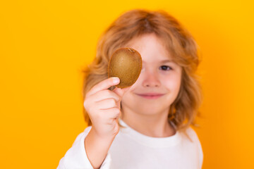 Vitamin and healthy fruits for kids. Child hold kiwi in studio. Kiwi fruit. Studio portrait of cute kid boy with kiwi isolated on yellow.