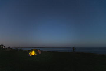 Fototapeta na wymiar Wild camping with a tent at night in summer. Starry sky, Paldiski cliff.