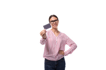 young positive secretary woman in glasses dressed in a red and white blouse holding a credit card with a mockup
