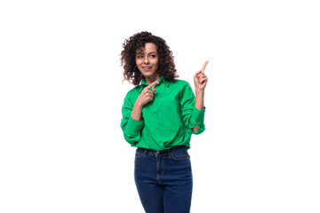 young slender brunette woman with curly hair in a green shirt points with her hand
