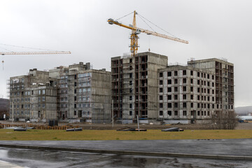 Construction of new multi-storey buildings. Construction of a residential complex. Apartment buildings. Housing construction. View of unfinished buildings and tower cranes.