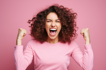 Happy mid adult woman screaming with clenched fists against pink background