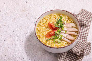 Spicy noodles with beef broth. Hot dish, cutlery, hard light, dark shadow. Stone concrete background