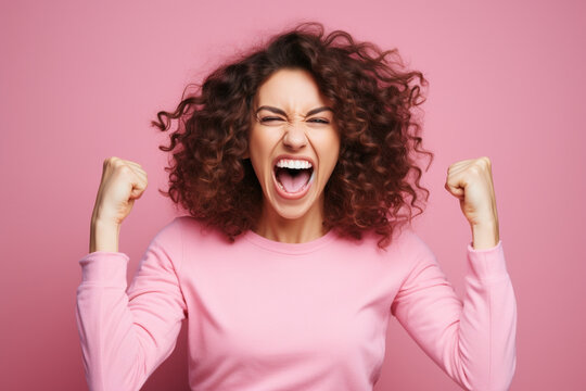 Happy mid adult woman screaming with clenched fists against pink background