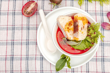 Tomato soup gazpacho ready to eat. Served portion, cutlery. The checkered tablecloth on the table