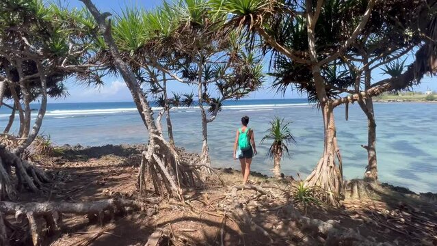 Hidden Gem of Nusa Dharma: 4K  Footage Showcasing Bali's Enchanting Beachfront with Hala Trees; Young Woman Explores the Serenity"