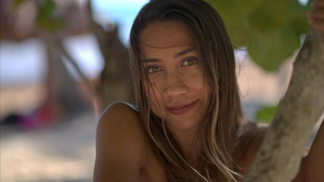Slow motion of a Young beautiful latin hispanic girl teasing smiling to the camera at a gorgeous beach in Mexico with the wind blowing her hair. Slow motion