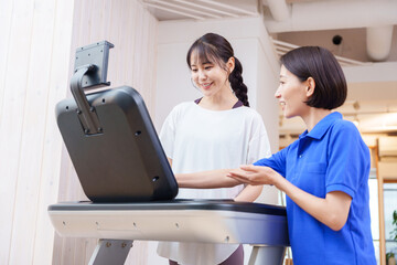 Fototapeta premium スポーツジムで運動する女性とトレーナー（ランニングマシン）