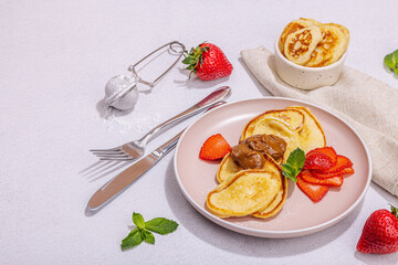 Cottage cheese pancakes, syrniki, curd fritters with strawberry, mint and powdered sugar on plate