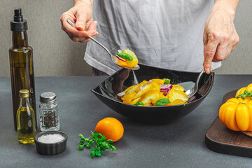 A woman is preparing a tomato salad. Ripe vegetables, herbs, aromatic spices, olive oil