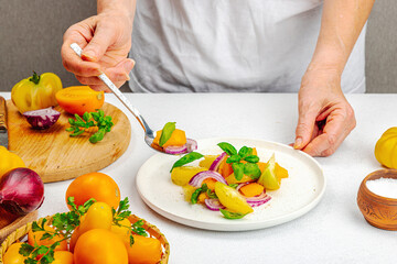 A woman is preparing a tomato salad. Ripe vegetables, herbs, aromatic spices, olive oil