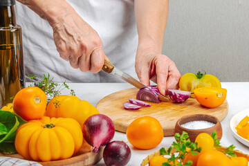 Obraz na płótnie Canvas A woman is preparing a tomato salad. Ripe vegetables, herbs, aromatic spices, olive oil