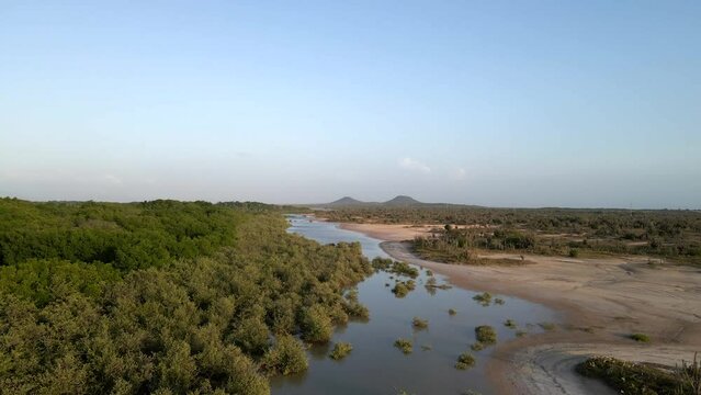 Drone follows this body of water with mangrove forest on the left side and sandbanks on the right also revealing the Tetas de Maria Guevara mountains,  Porlamar, Margarita Island, Venezuela