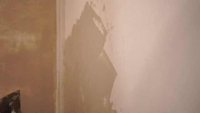 Male builder use metal spatula for putty walls, repairman filling spatula with spackling paste and covering cement wall surface. Builder leveling wall and angle Renovation work in Residential Premises
