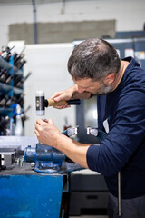 Professional man working on a steel piece with hammer in a metal factory workshop. Industrial mechanics and repairs