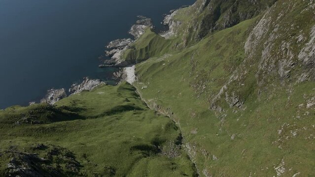 Aerial top down shot of Norwegian Hoddevik mountains with green mountains and blue ocean in summer